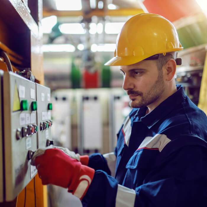 Elektriker arbeitet in der Produktionshalle an den Stromschalert.