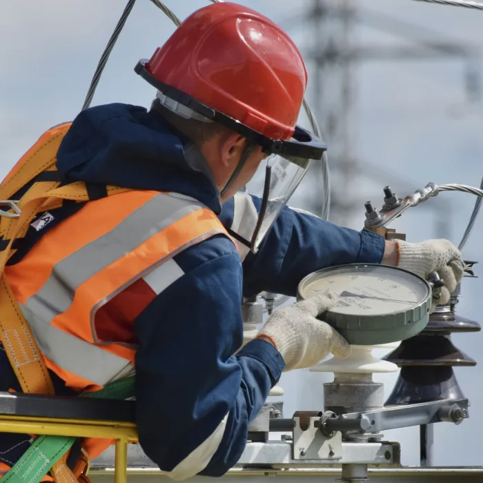 Ein Elektroinstallateur bei der Wartung von Übertragungsleitungen