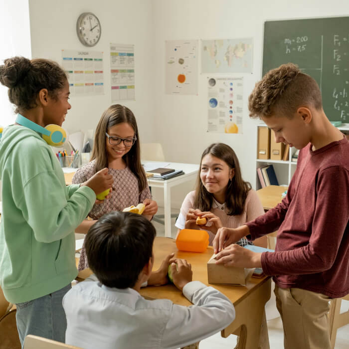 Sozialpädagogin mit einer Gruppe Kinder in einem Klassenzimmer. Gerade beim Frühstücken.